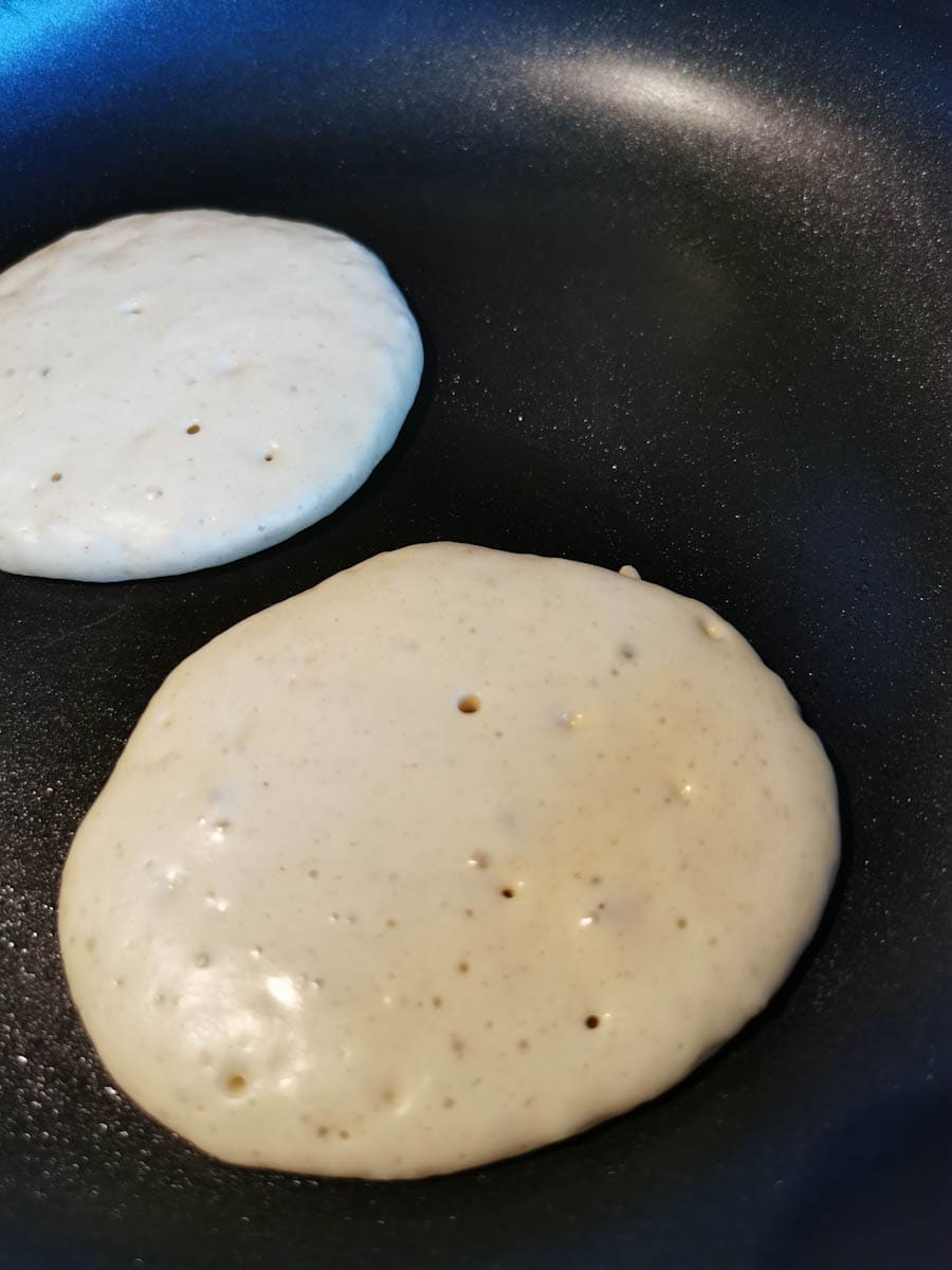 two pancakes cooking in a frying pan