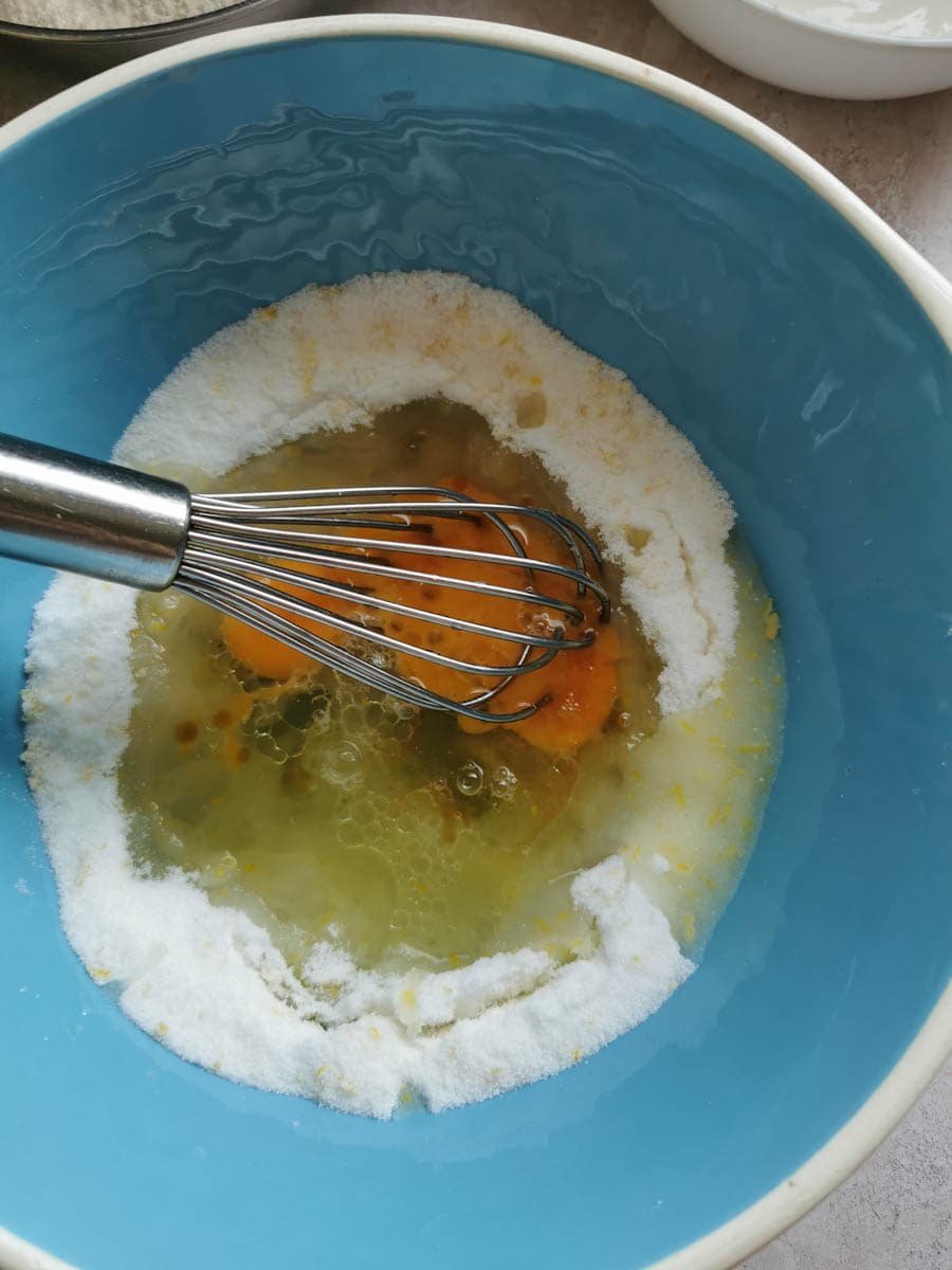 a blue and white bowl of eggs and oil being whisked to make a cake batter.