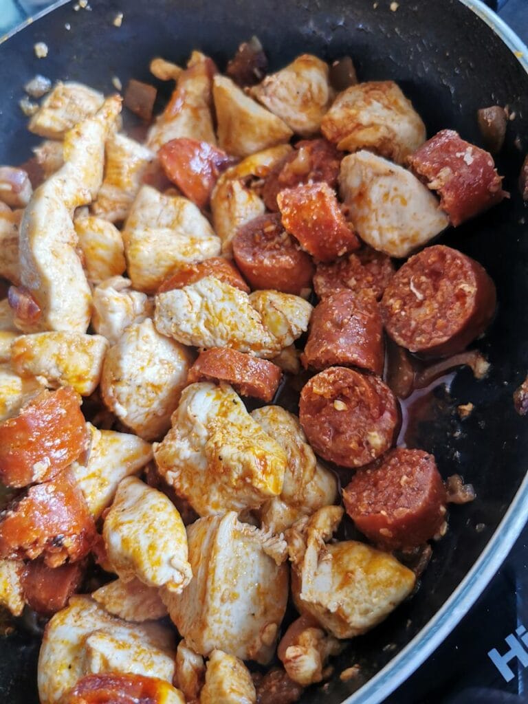 Chicken chunks and chorizo cooking in a frying pan