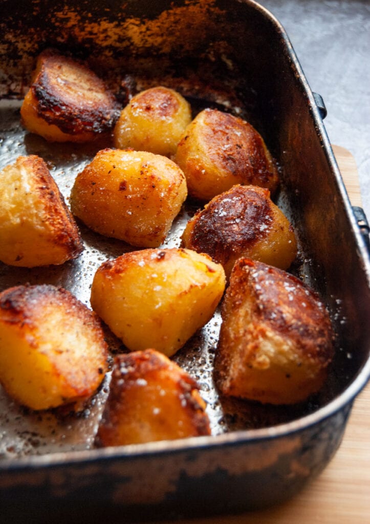 a roasting tin of roast potatoes sprinkled with salt.