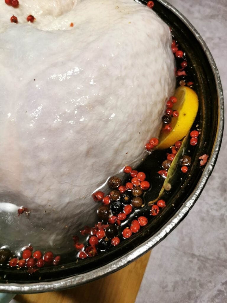 a turkey crown brining in a pot of water, orange slices and spices.