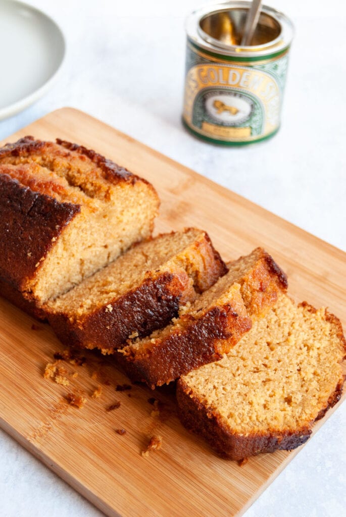 a partially sliced golden loaf cake on a wooden board.