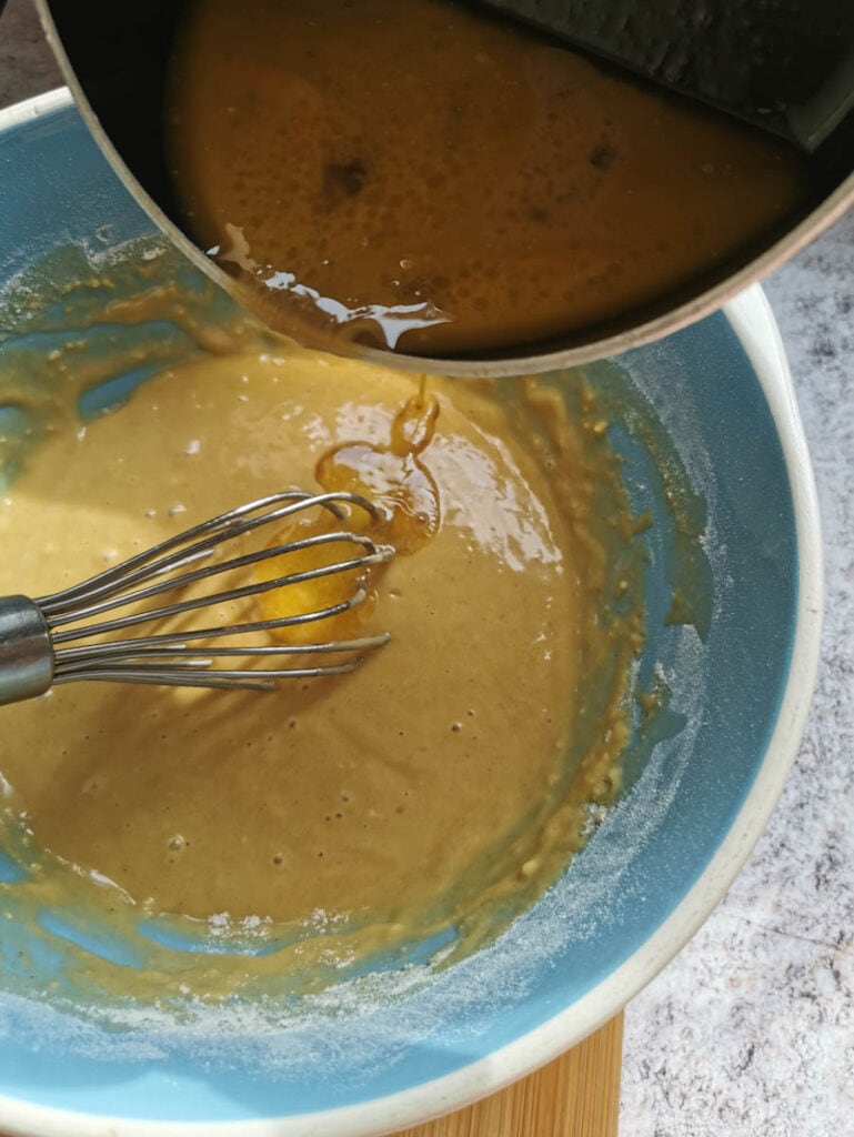 melted syrup and butter being poured into a cake batter.