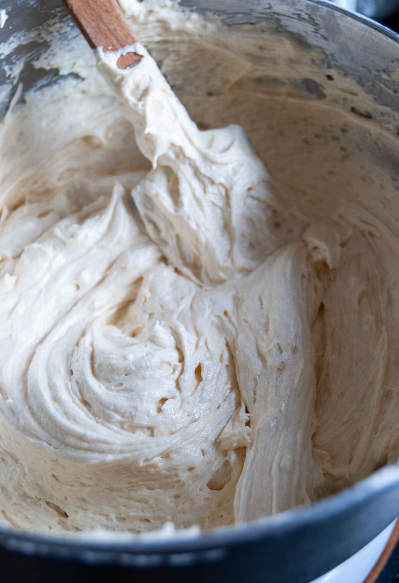 vanilla cake batter with a wooden spatula in a silver mixing bowl