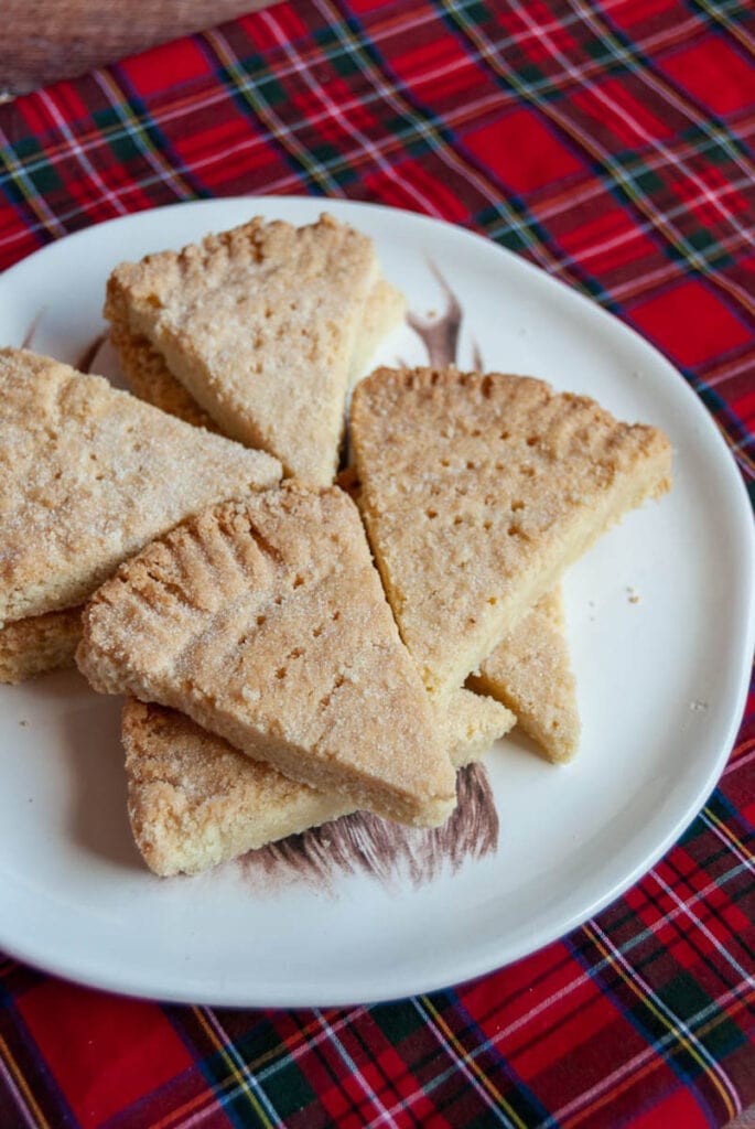 Shortbread petticoat tails on a white plate and a tartan tablecloth.