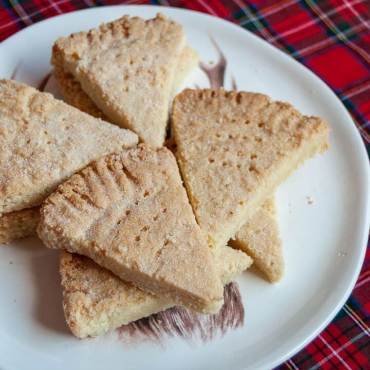 Shortbread petticoat tails on a white plate and a tartan tablecloth.