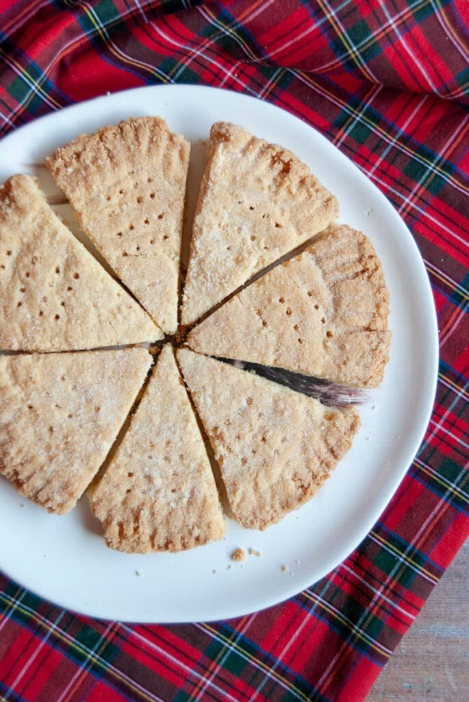 a plate of shortbread petticoat tails on a white plate and a tartan tablecloth.