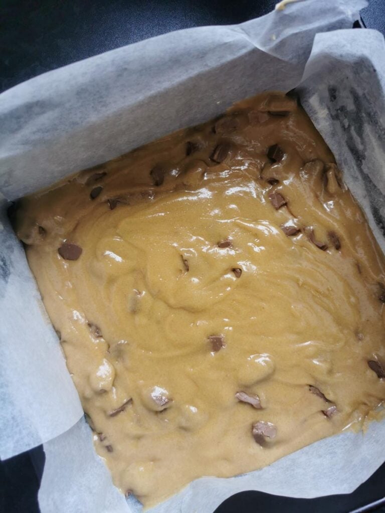 a square pan of chocolate chip cookie dough lined with baking paper