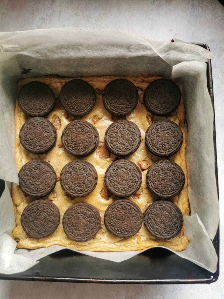 a square pan of chocolate chip cookie dough with 16 Oreo cookies.