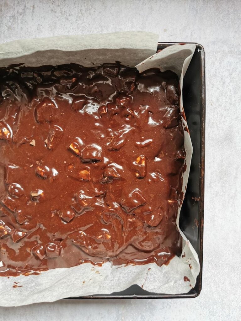 a square pan of unbaked chocolate brownie batter lined with baking paper