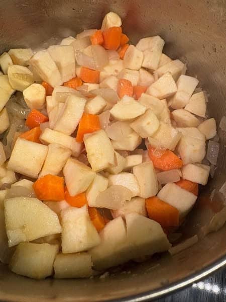 Diced parsnips, carrots and onions in a silver saucepan.