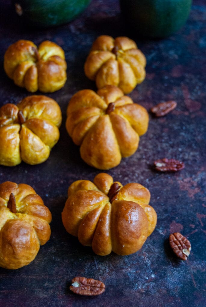 six pumpkin shaped rolls with a pecan nut stalk.