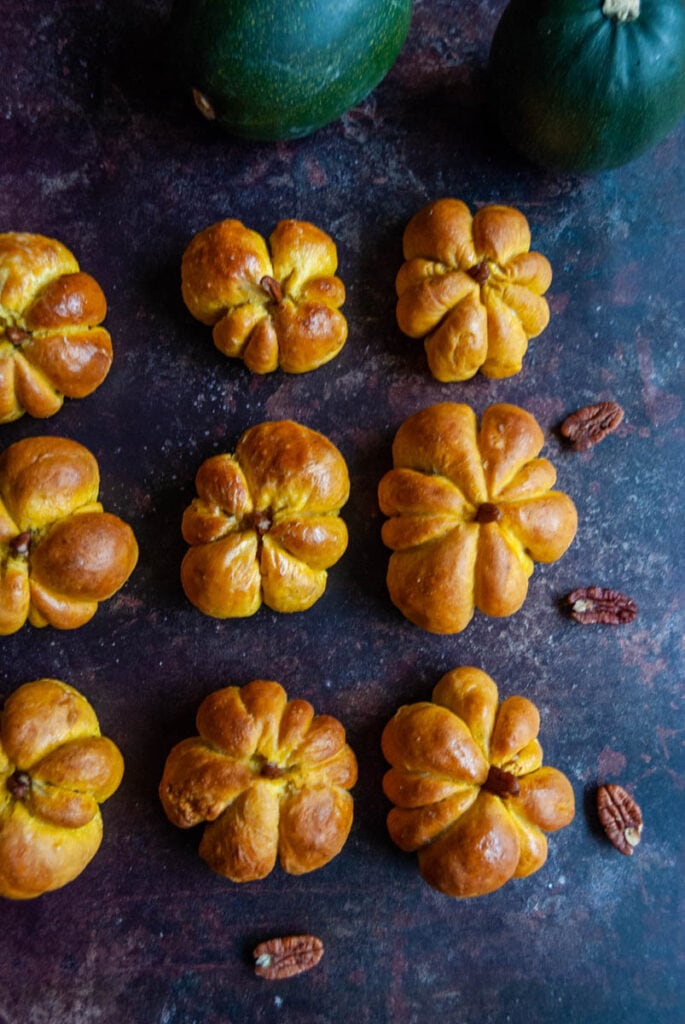 nine pumpkin shaped bread rolls with a pecan nut stalk. 