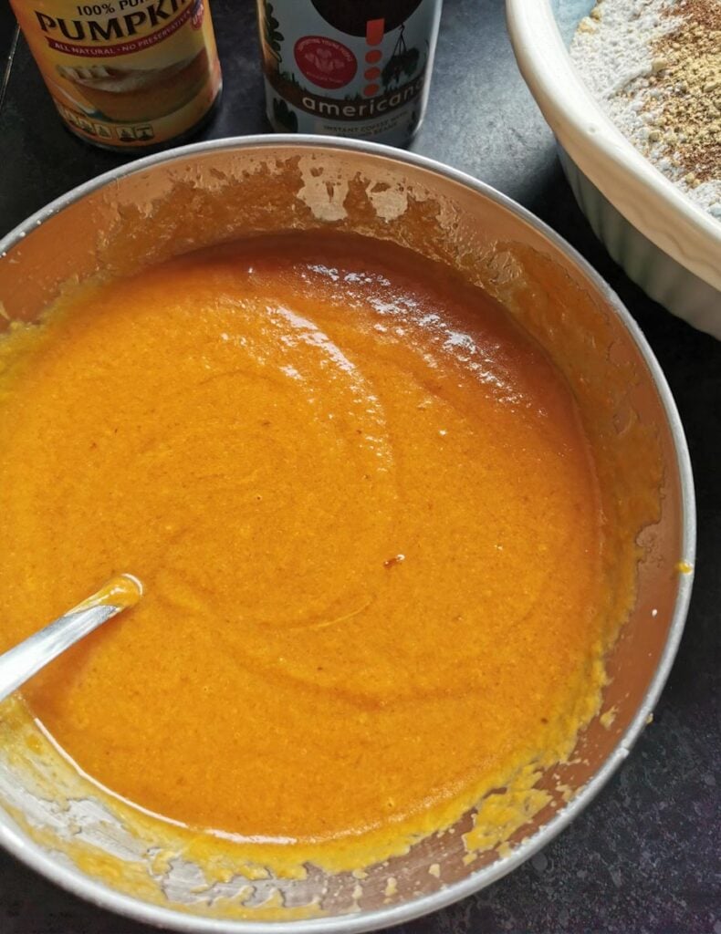 A silver bowl of pumpkin purée, oil and eggs.