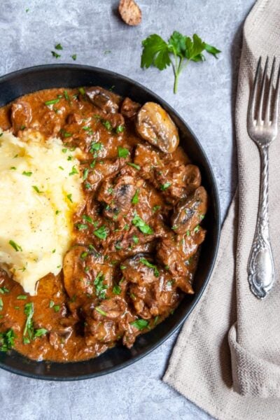 a plate of beef stroganoff with mushrooms and mashed potatoes