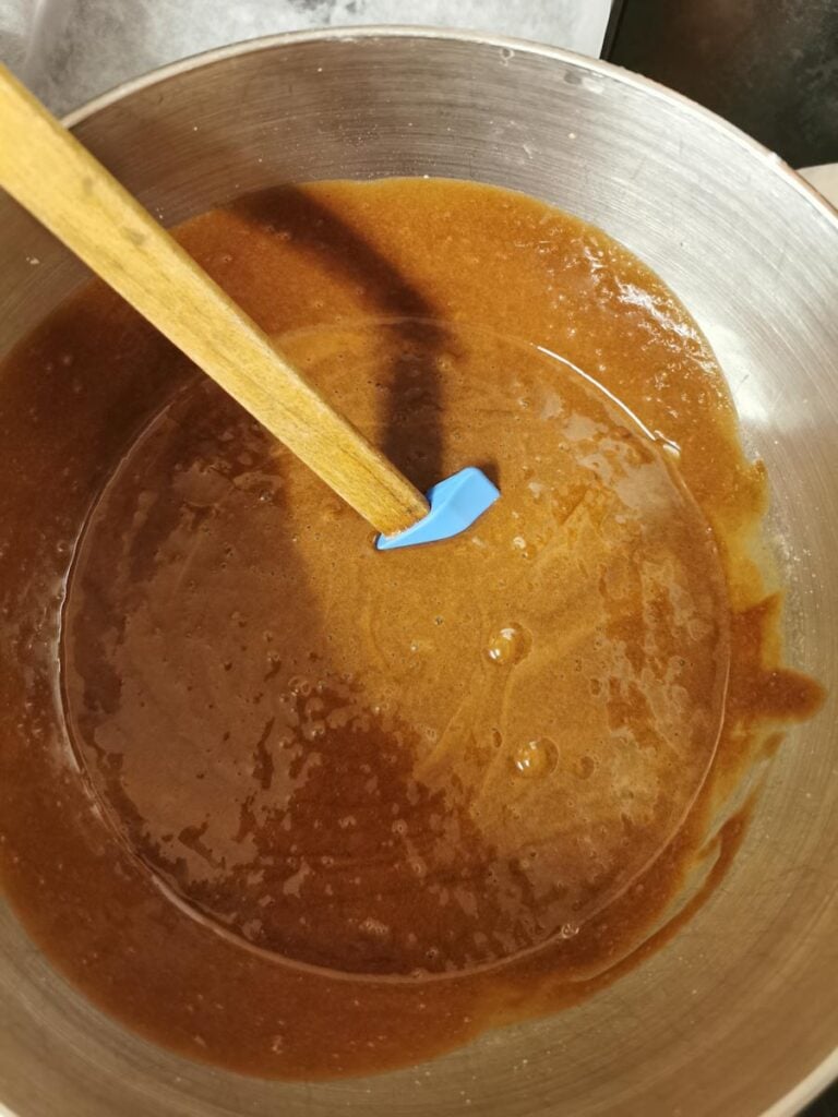 a silver bowl of chocolate brownie batter with a wooden spatula