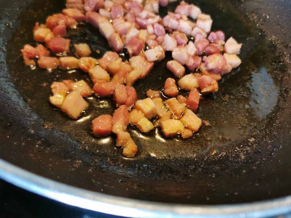 pancetta cubes frying in a pan