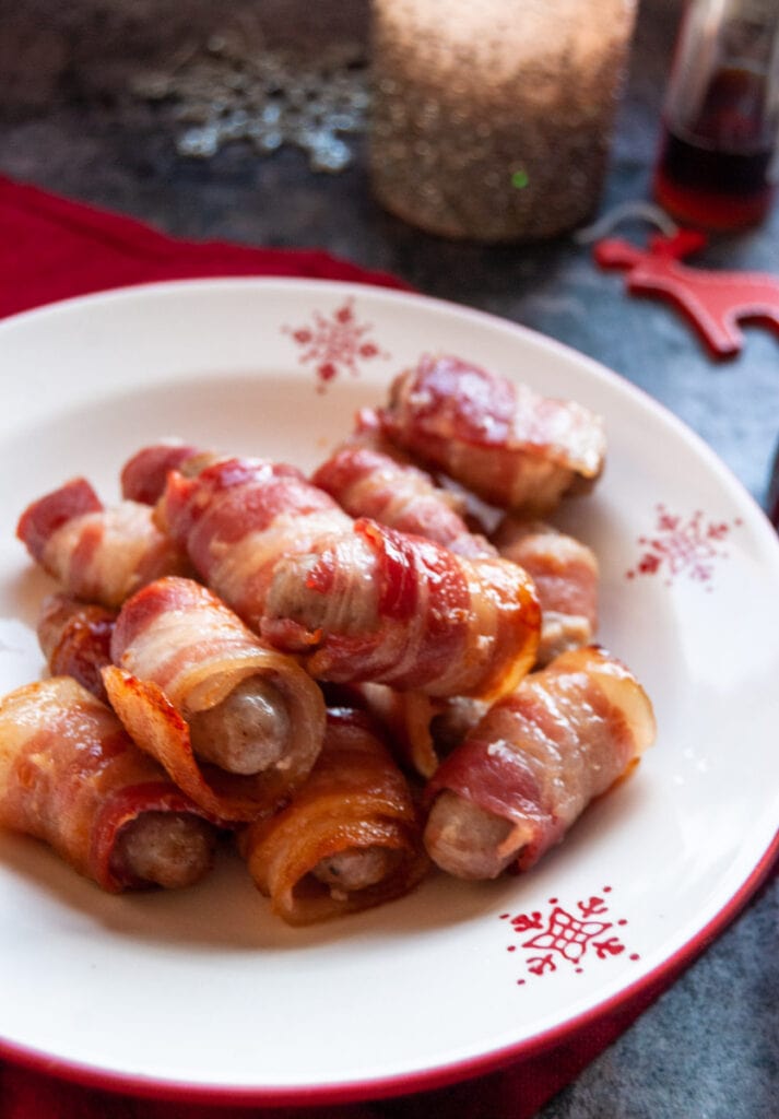 a red and white Christmas bowl of little sausages wrapped in bacon.