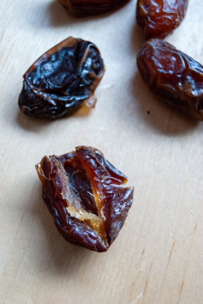 Medjool dates cut down the middle on a wooden chopping board