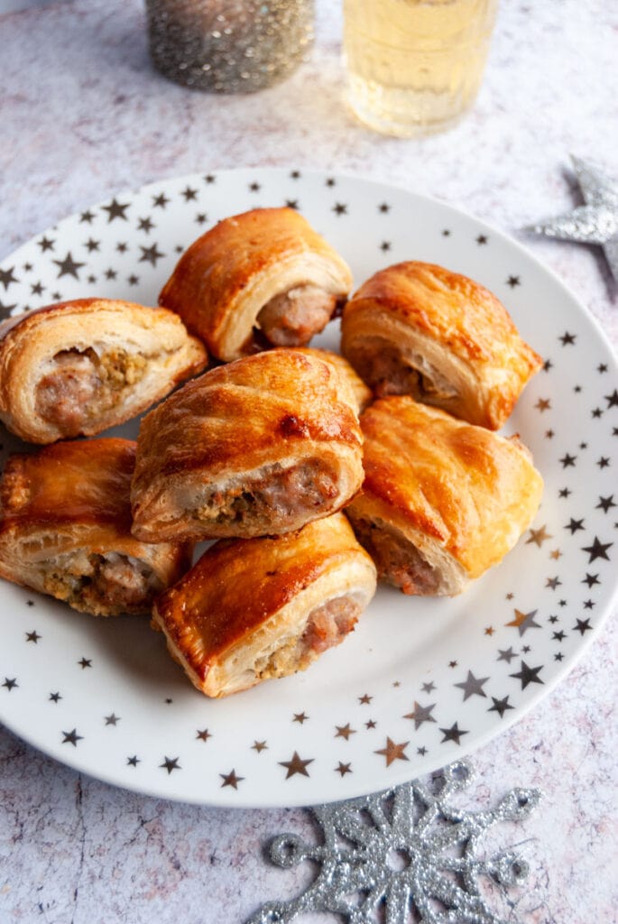 a white and silver star plate of puff pastry sausage rolls.