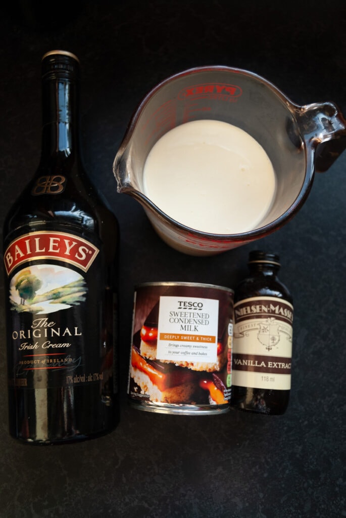 a bottle of baileys Irish cream, a tin of condensed milk, a bottle of vanilla extract and a jug of double cream.