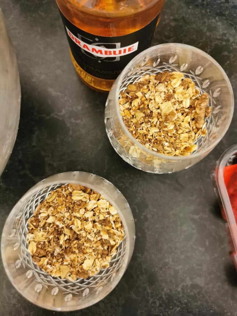 two glasses filled with toasted oats and a bottle of Drambuie.