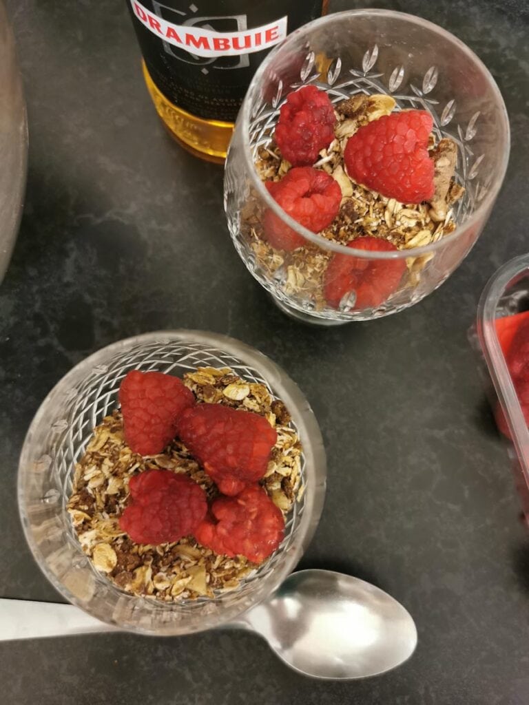 two crystal glassses filled with toasted oats, nuts and raspberries and a bottle of Drambuie Liqueur. 