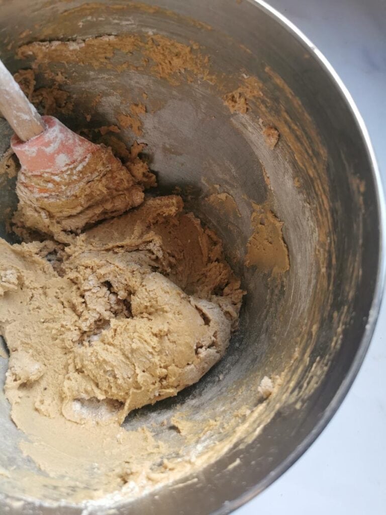 a silver bowl of thick cake batter and a wooden handled spatula,