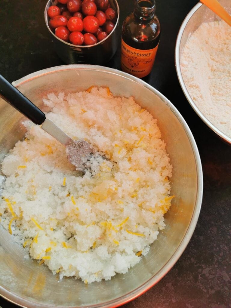 a silver bowl of sugar, orange zest and oil with a fork.