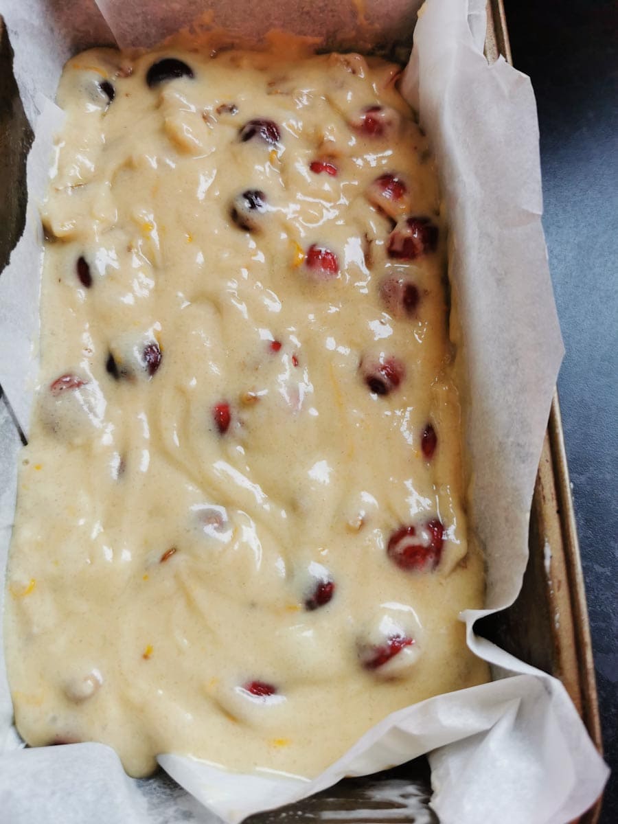 an unbaked orange and cranberry loaf cake in a loaf pan.