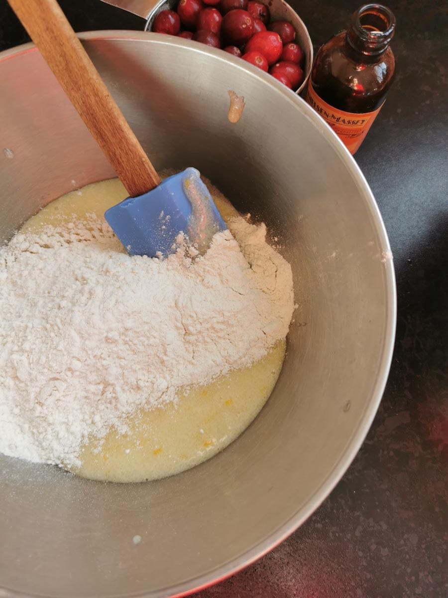Flour being folded into a silver bowl of cake batter.