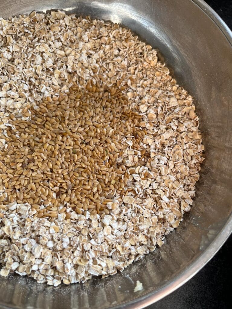 a silver bowl of rolled oats and golden linseeds