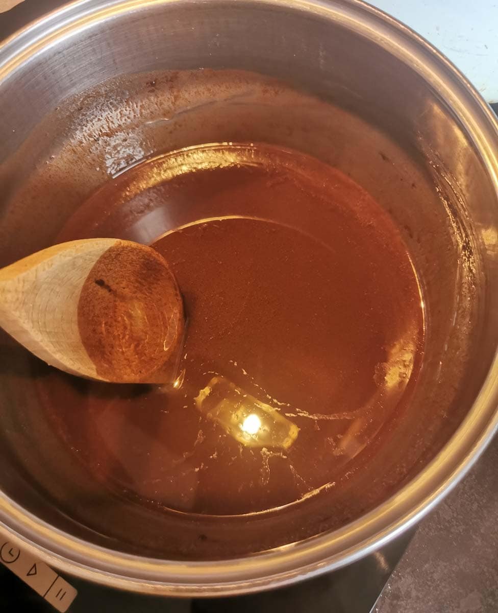 Melted Butter and chocolate in a saucepan with a wooden spoon.