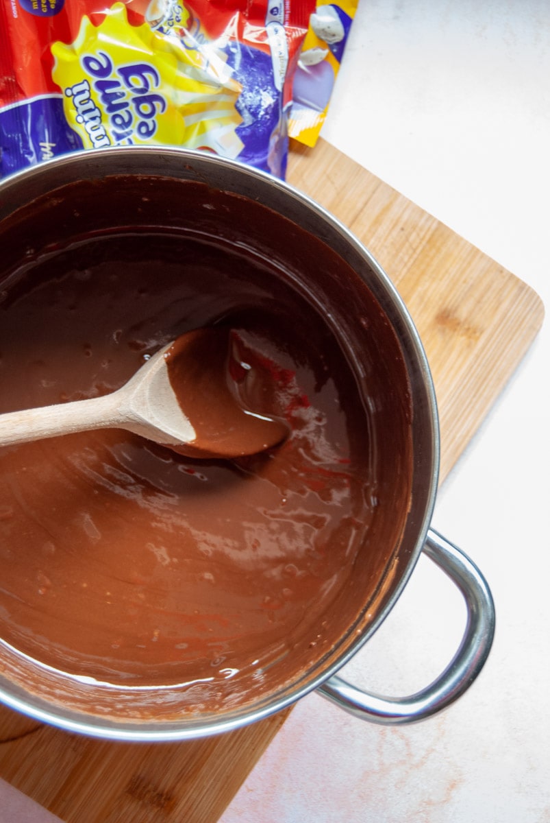 a silver pan of melted chocolate with a wooden spoon.