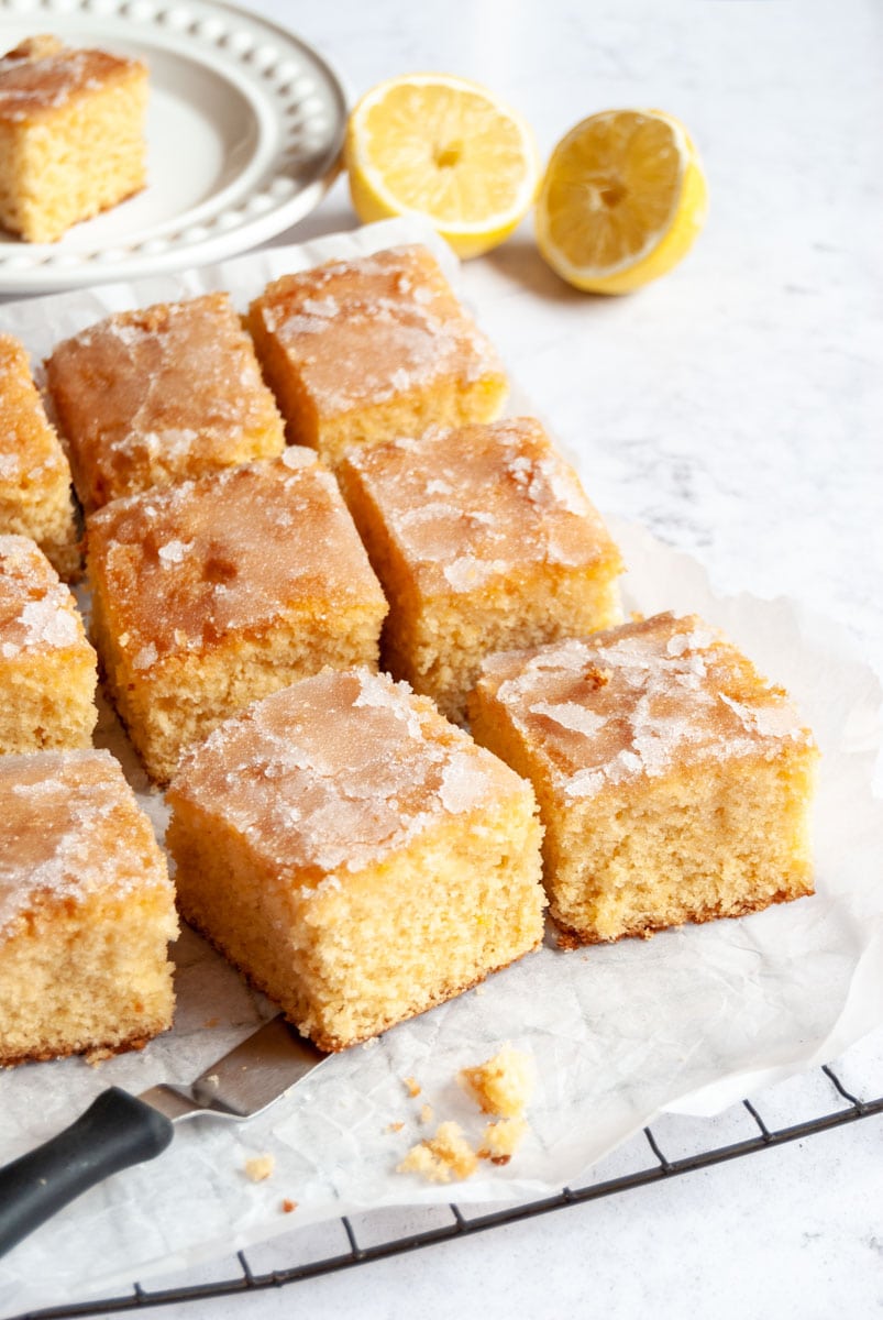 Squares of lemon drizzle cake on a wire cooling rack.