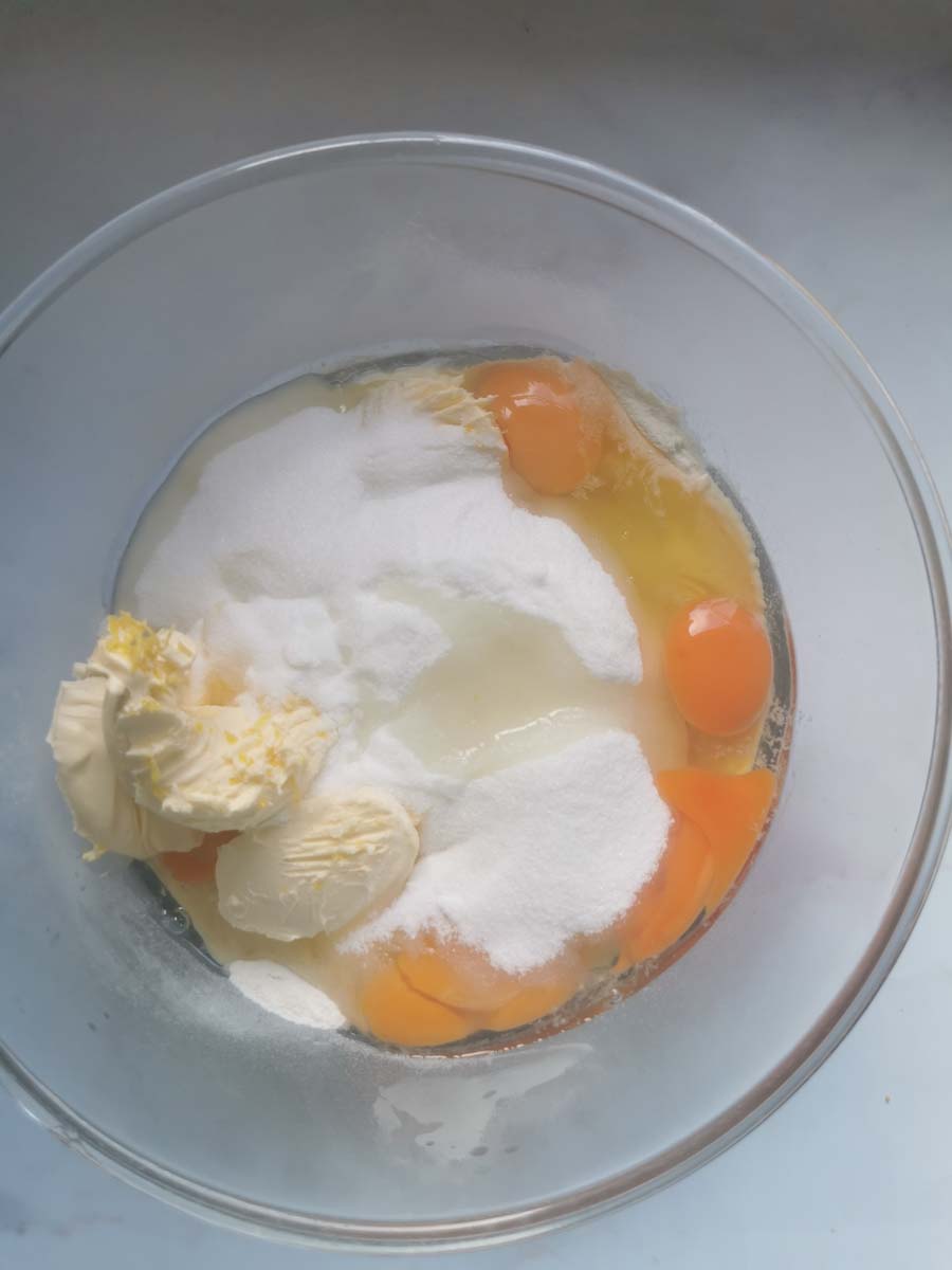 a large glass mixing bowl of butter, sugar, eggs and flour for making a cake.