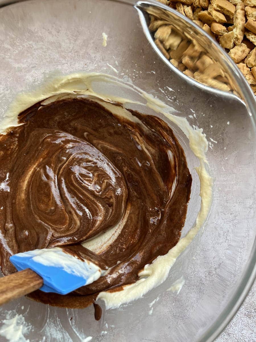 melted chocolate being stirred into a bowl of creamed butter and sugar.