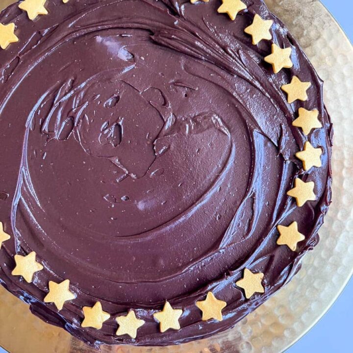 a large round no bake chocolate cake decorated with gold stars on a gold cake stand.