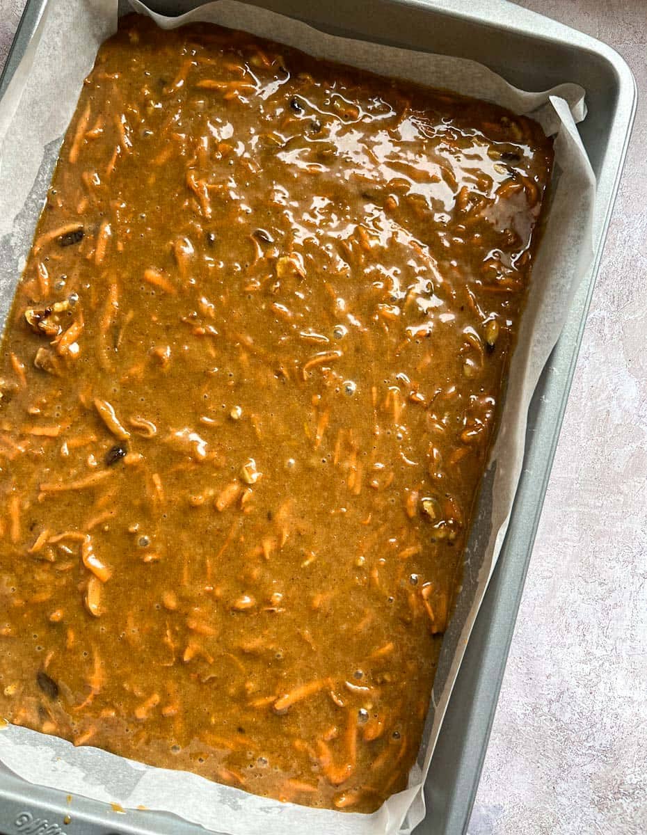 carrot cake batter poured into a rectangular silver baking tin.