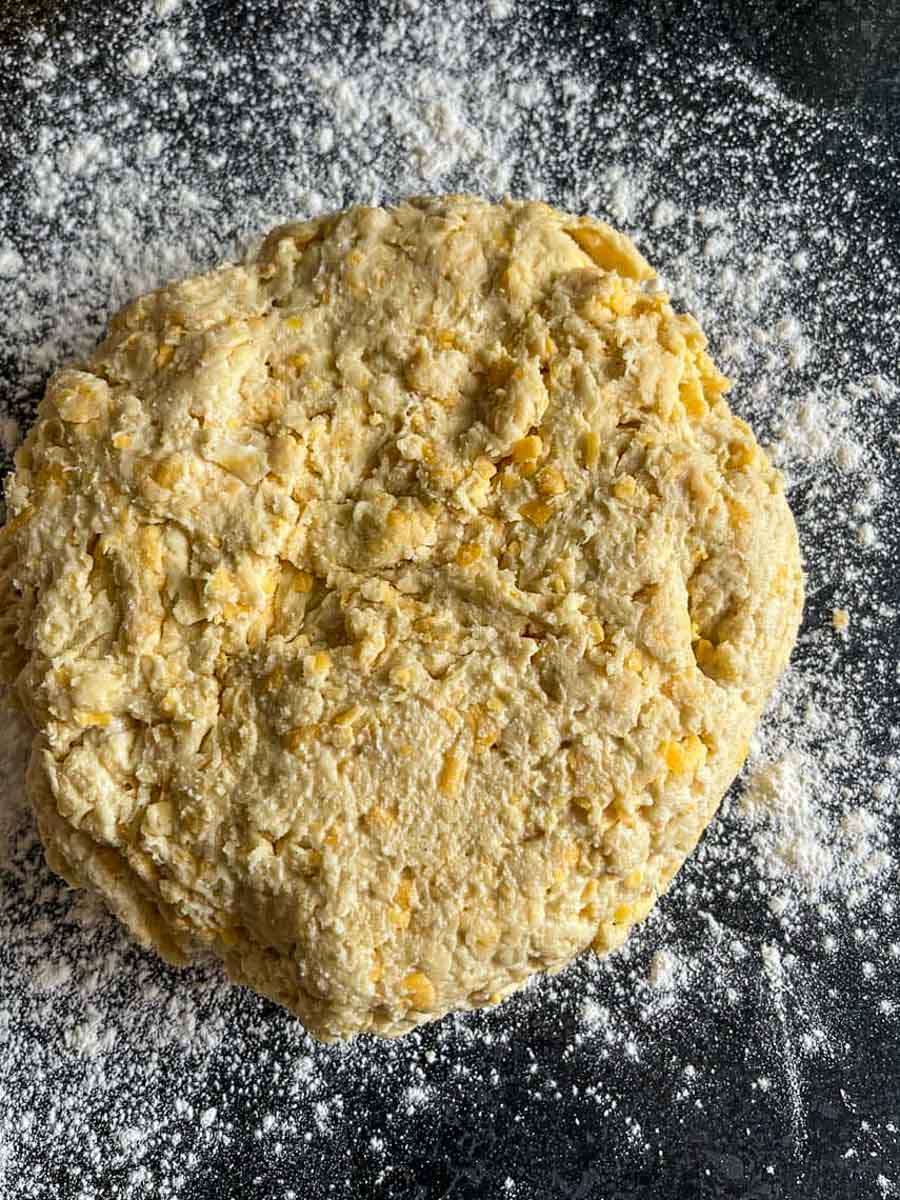 a circle of unbaked cheese scone dough on a floured work surface.