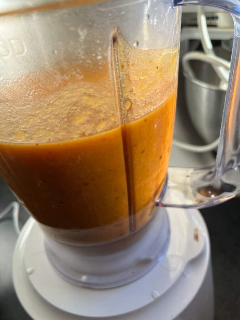 a white electric blender blending butternut squash soup.