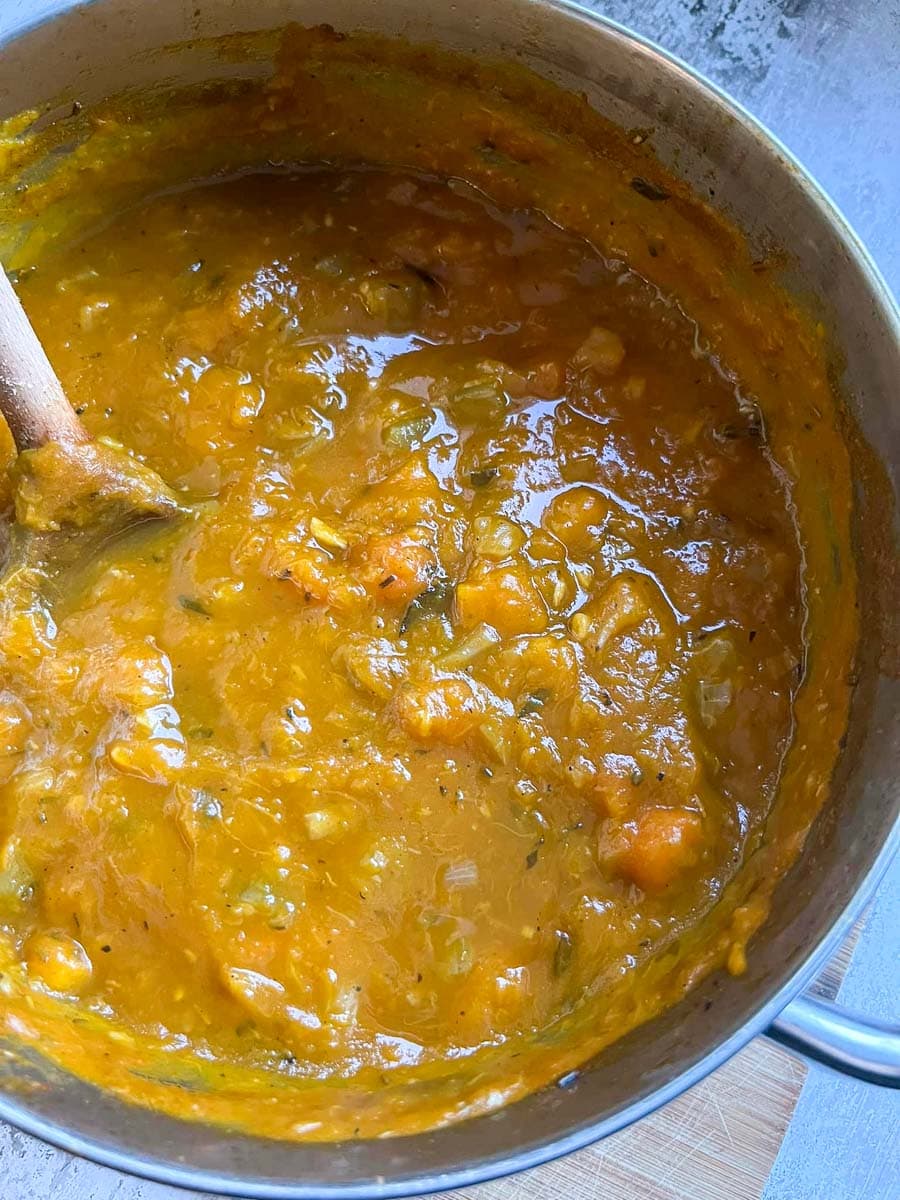 a chunky pumpkin soup in a large silver pan.