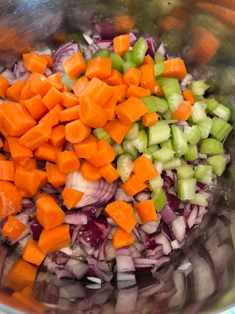 chopped red onion, celery and carrots in a silver pan.