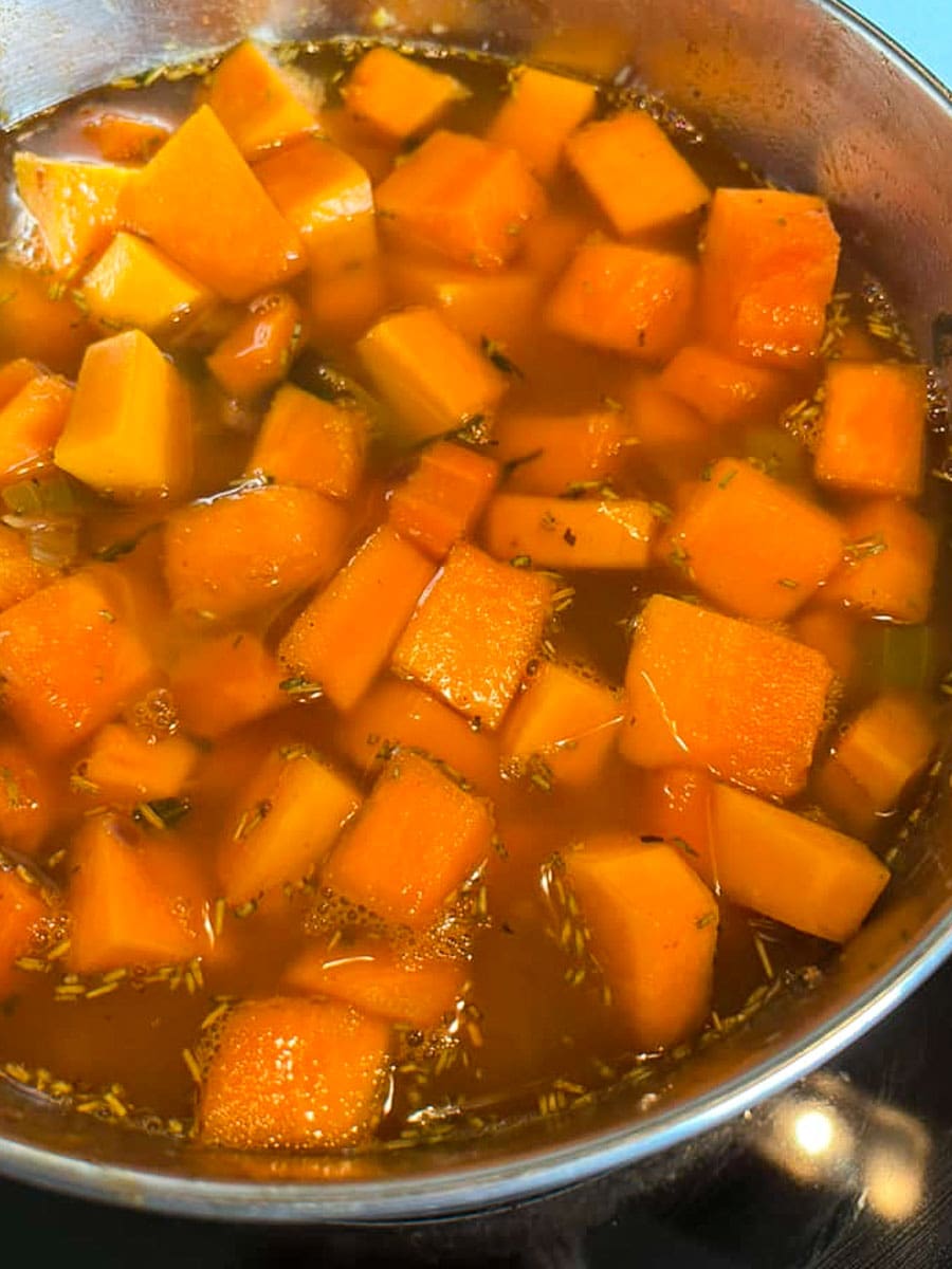 diced pumpkin, onion, carrot,celery and vegetable stock in a large silver pan.