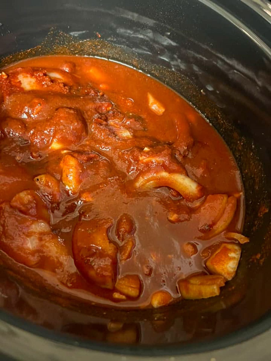 chicken pieces coated in BBQ sauce inside a slow cooker.