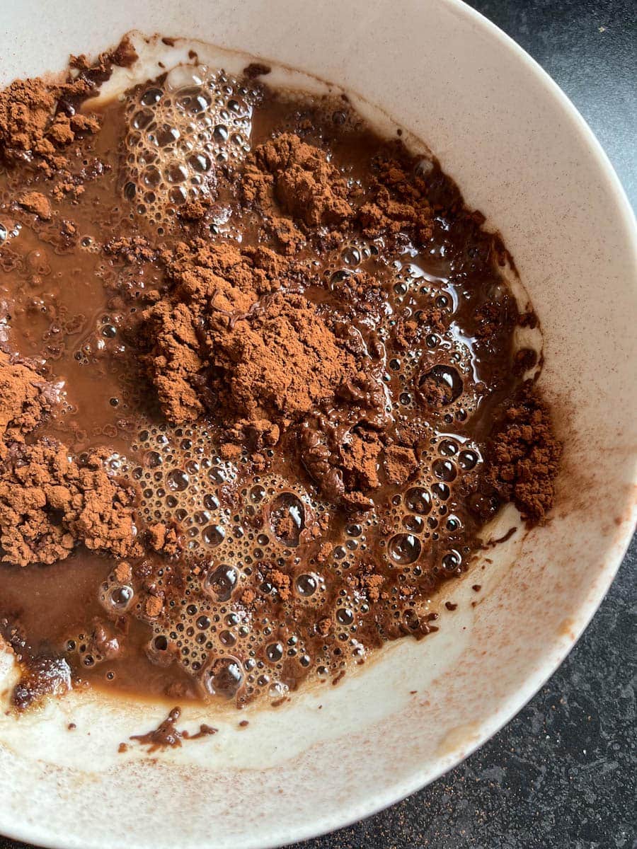a white bowl of cocoa powder, sugar and boiling water.