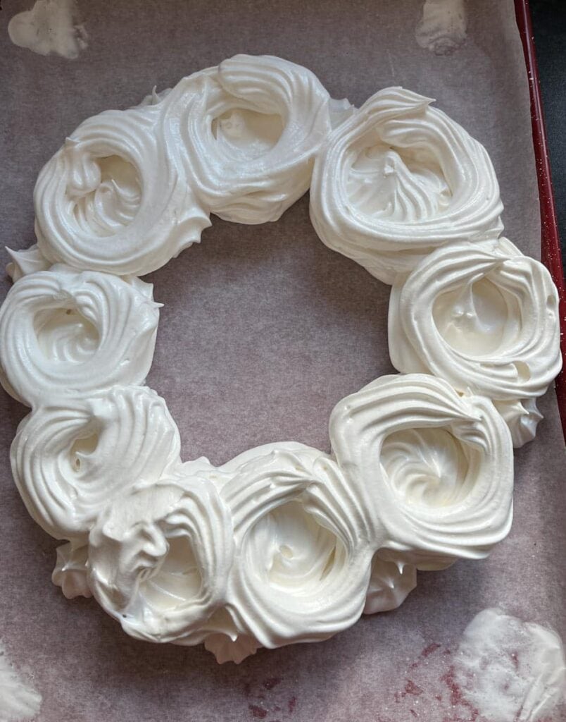 meringue piped in the shape of a wreath on a lined baking tray.