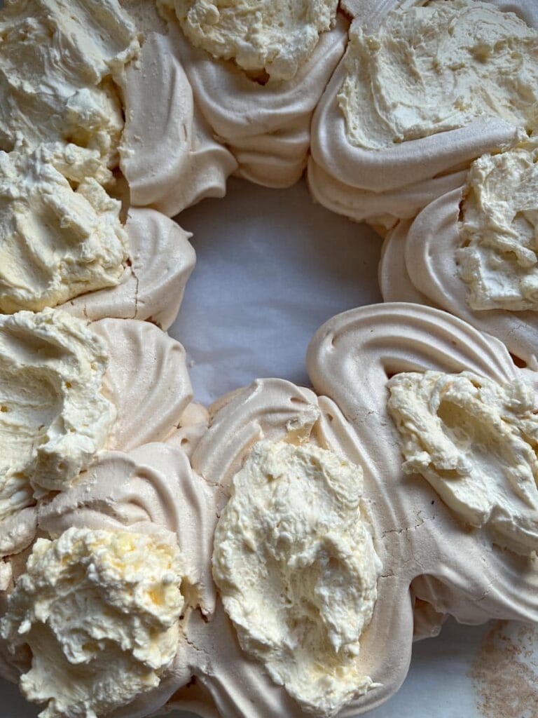 a wreath shaped pavlova filled with whipped cream.