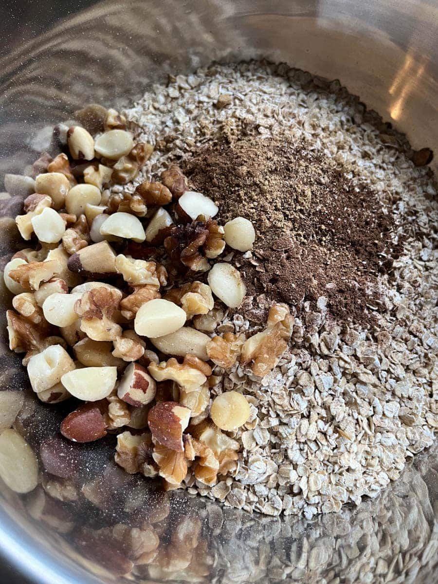 a silver bowl of oats, spices and mixed nuts.