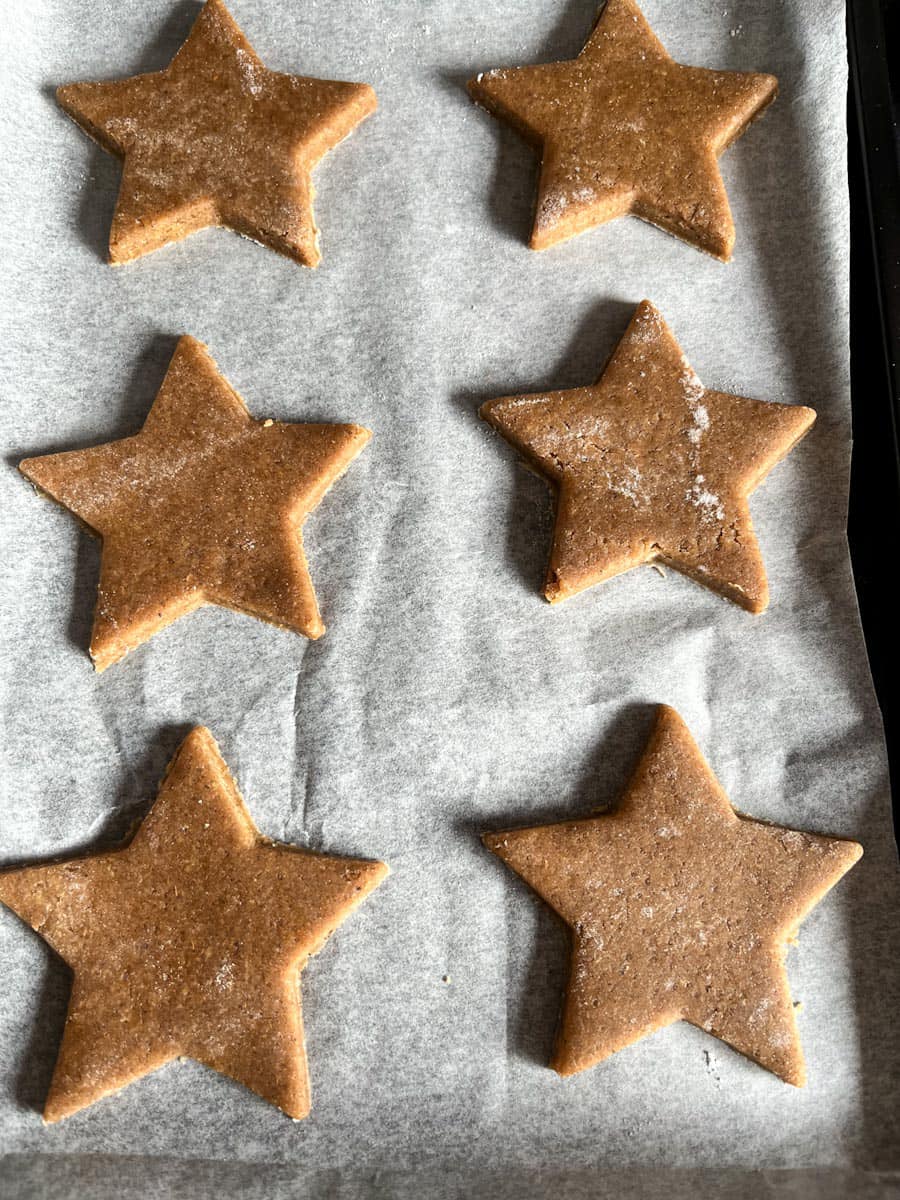 six unbaked star shaped cookies on a parchment lined baking tray.